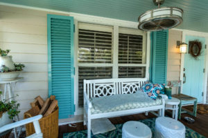 Teal blue colonial shutters opened out on a front porch window