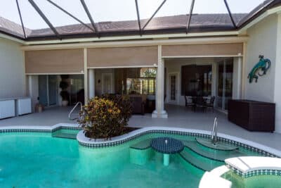 Roll-down screens separating a home from an outdoor living space with a pool