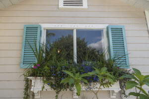 Tan home with teal colonial shutters on a window.