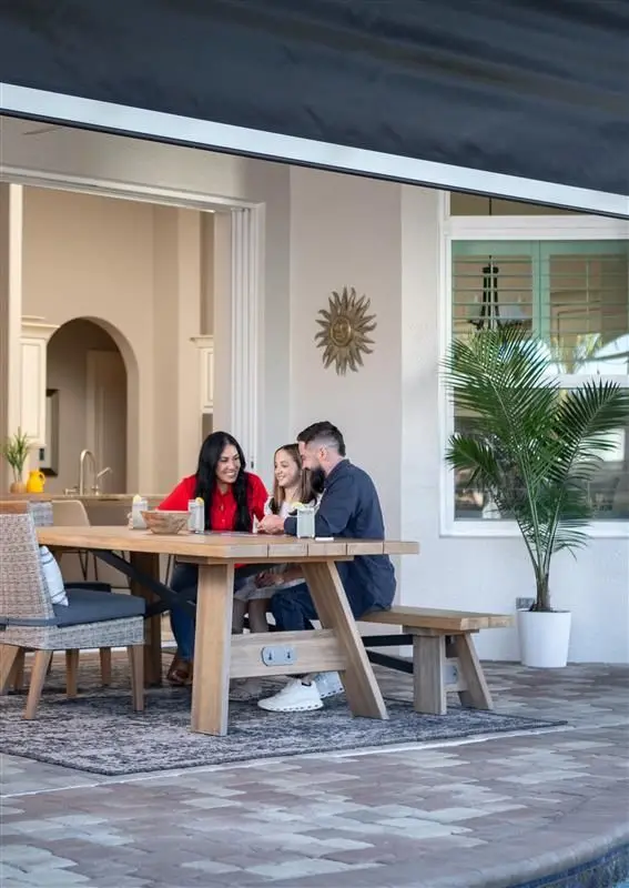 Family sitting on picnic table on patio with roll down screen